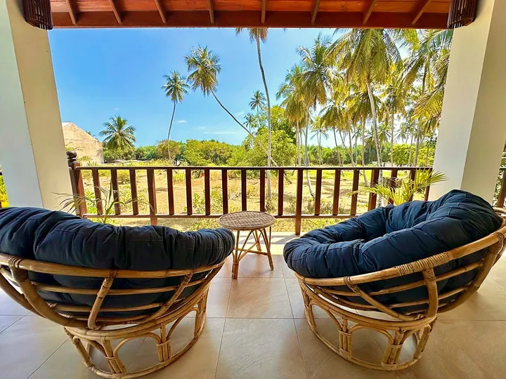 Private balcony with rattan chairs overlooking palm trees