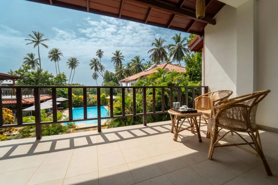 Balcony with wicker chairs over palms and the pool
